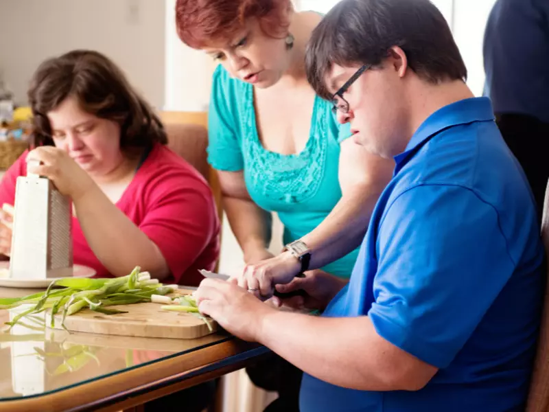 Two disabled friends in a cooking class with carer