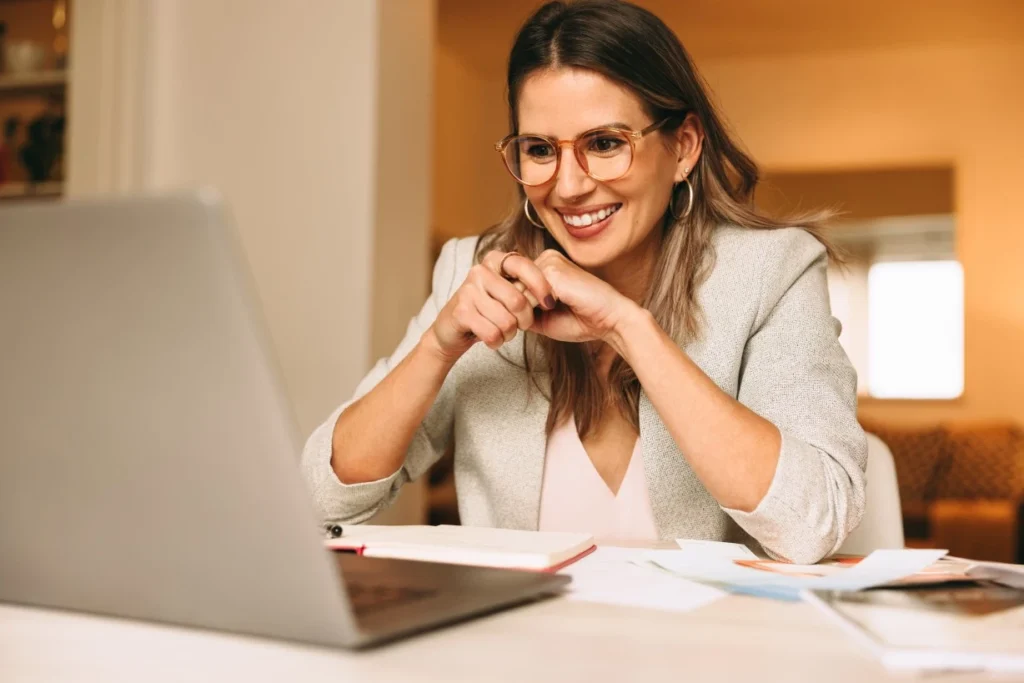 Happy woman smiling at laptop while making NDIS referral