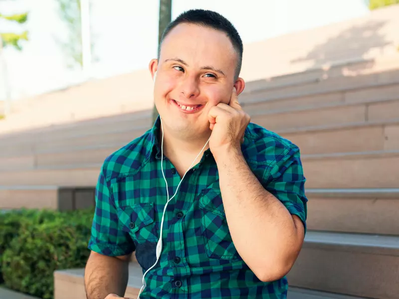 Disabled boy smiling with headphones in while on the phone